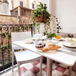 Tavolo apparecchiato per la colazione sul balcone privato del B&B, con brioche e cappuccino e vista sui palazzi storici.