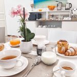 Tavolo pronto per una colazione completa con brioche, muffin, tazza di tè caldo, latte e caffè espresso nel nostro B&B.
