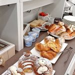 Angolo colazione con frutta di stagione, spremute d'arancia e pasticceria tipica siciliana.