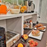 Dettaglio del buffet con ciotole di frutta fresca di stagione, come pesche e ciliegie, per una colazione salutare.