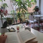 Momento di relax mattutino leggendo un libro sulla terrazza fiorita del B&B a Palermo, accompagnato da un caffè.